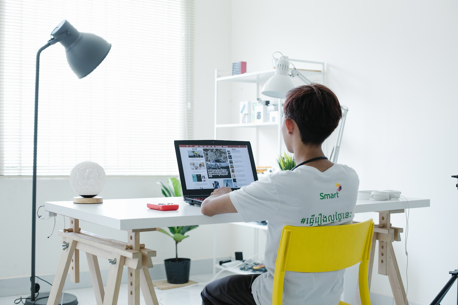 woman in white shirt sitting on chair using laptop computer