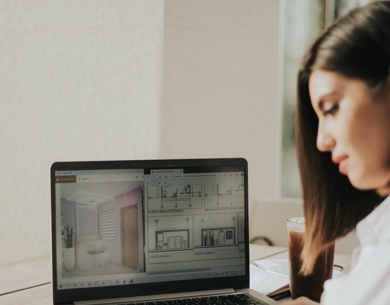 Kobieta skupiająca się na planach architektonicznych na laptopie